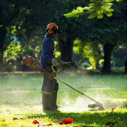 Picture of a man cutting grass with a strimmer.